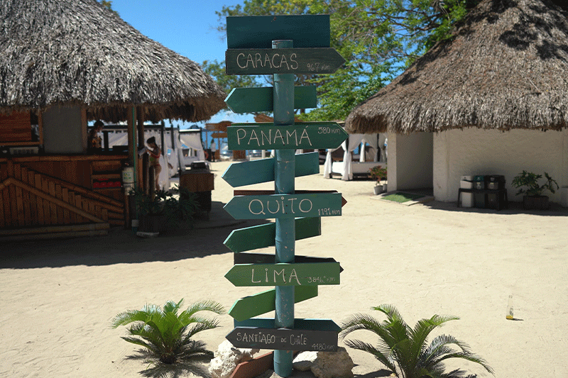 signs at bora bora beach club showing the distance and miles from cities all over the world